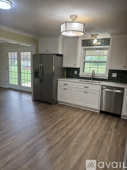 A kitchen with a refrigerator, cabinets, and a window.