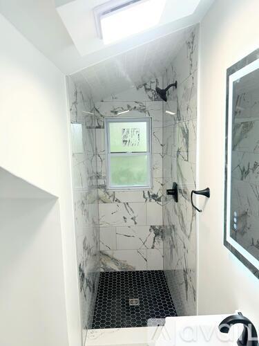 A bathroom with a marble shower stall and a glass door.