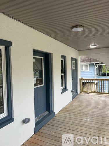 A balcony with a dark blue door and a white wall.