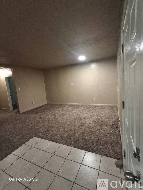 A room with a carpeted floor and a door on the right side.