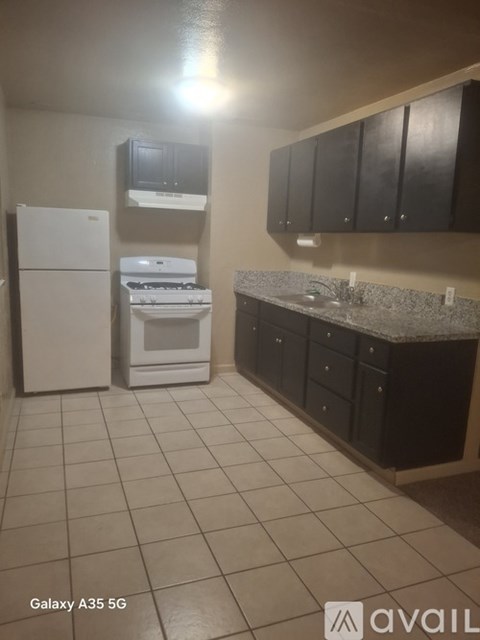 A kitchen with black cabinets and a white fridge.