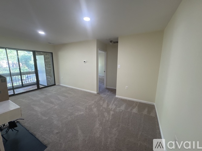 A spacious room with a carpeted floor and a door leading to another room.