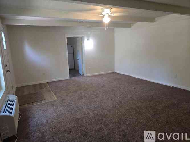 A room with a carpeted floor and a ceiling fan.