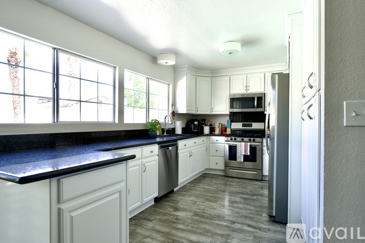 A kitchen with white cabinets and black countertops.