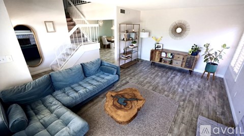 A living room with a blue couch and a brown rug.