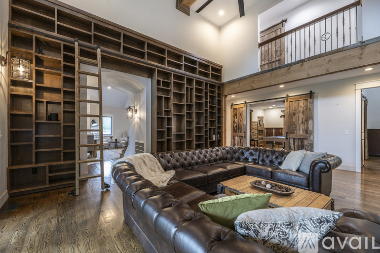 A living room with a leather couch and a wooden bookshelf.