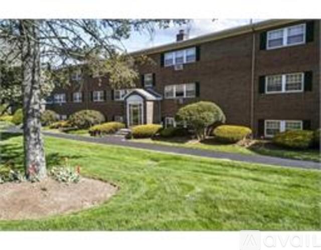 A tree in a landscaped yard in front of a brick apartment building.