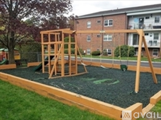 A playground with a wooden swing set and a green slide.