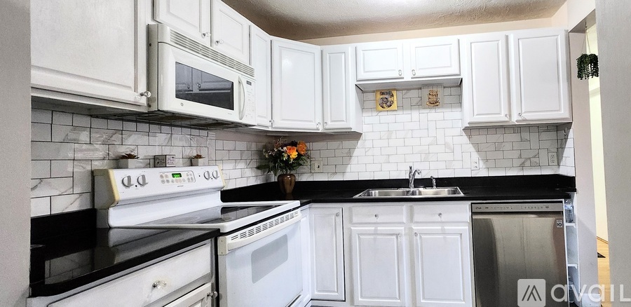 A white kitchen with black countertops and white cabinets.