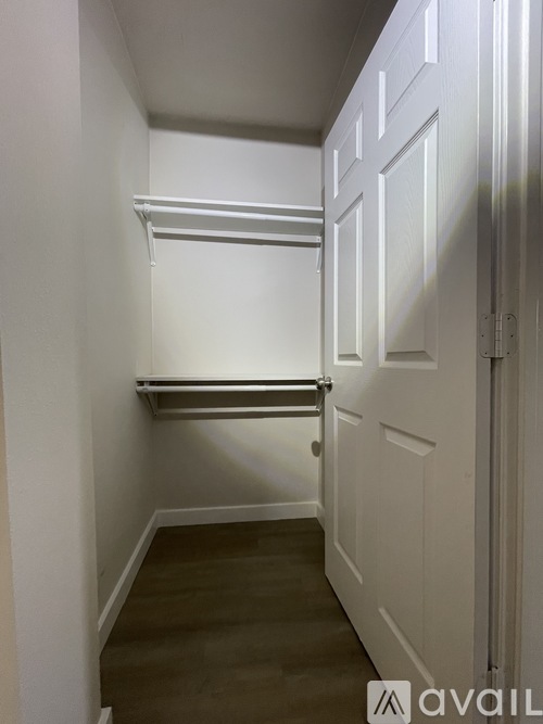 A white hallway with a shelf and a door.