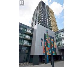 A tall building with a mural on the side of a low building.