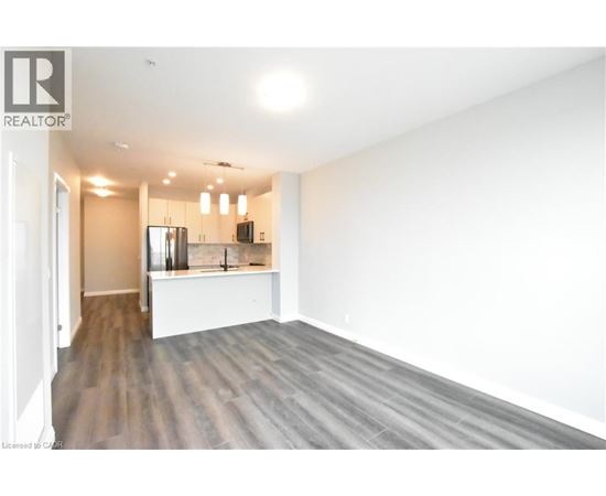 A spacious room with wooden flooring and white walls.
