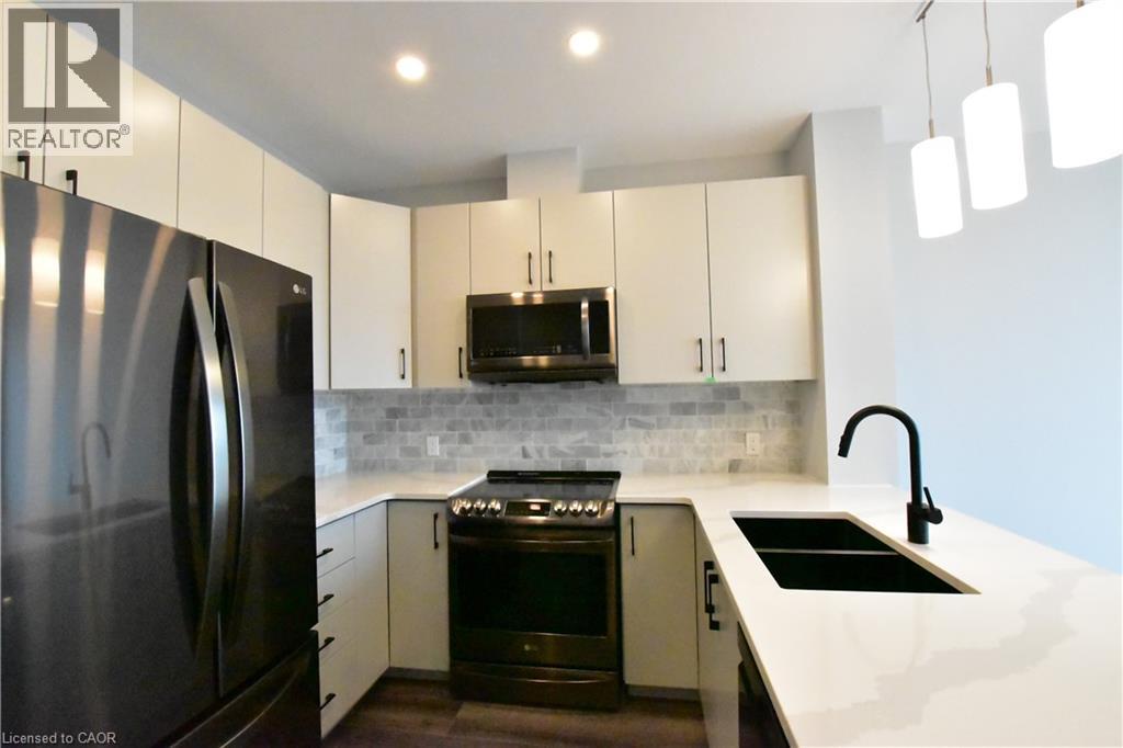 A modern kitchen with a black refrigerator and white countertops.