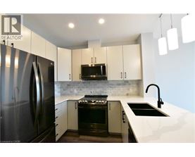 A modern kitchen with a black refrigerator and white countertops.