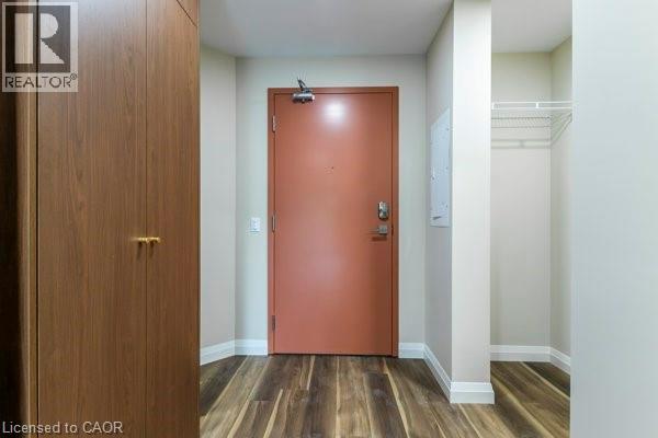A hallway with a brown door and a wooden floor.