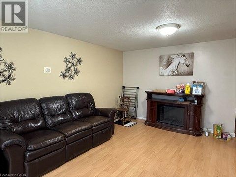 A living room with a black leather couch and a wooden entertainment center.