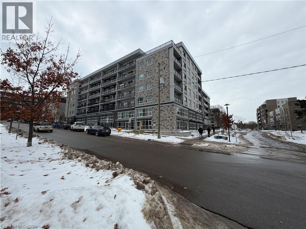 A large building with a grey facade is situated on a street with snow on the ground.
