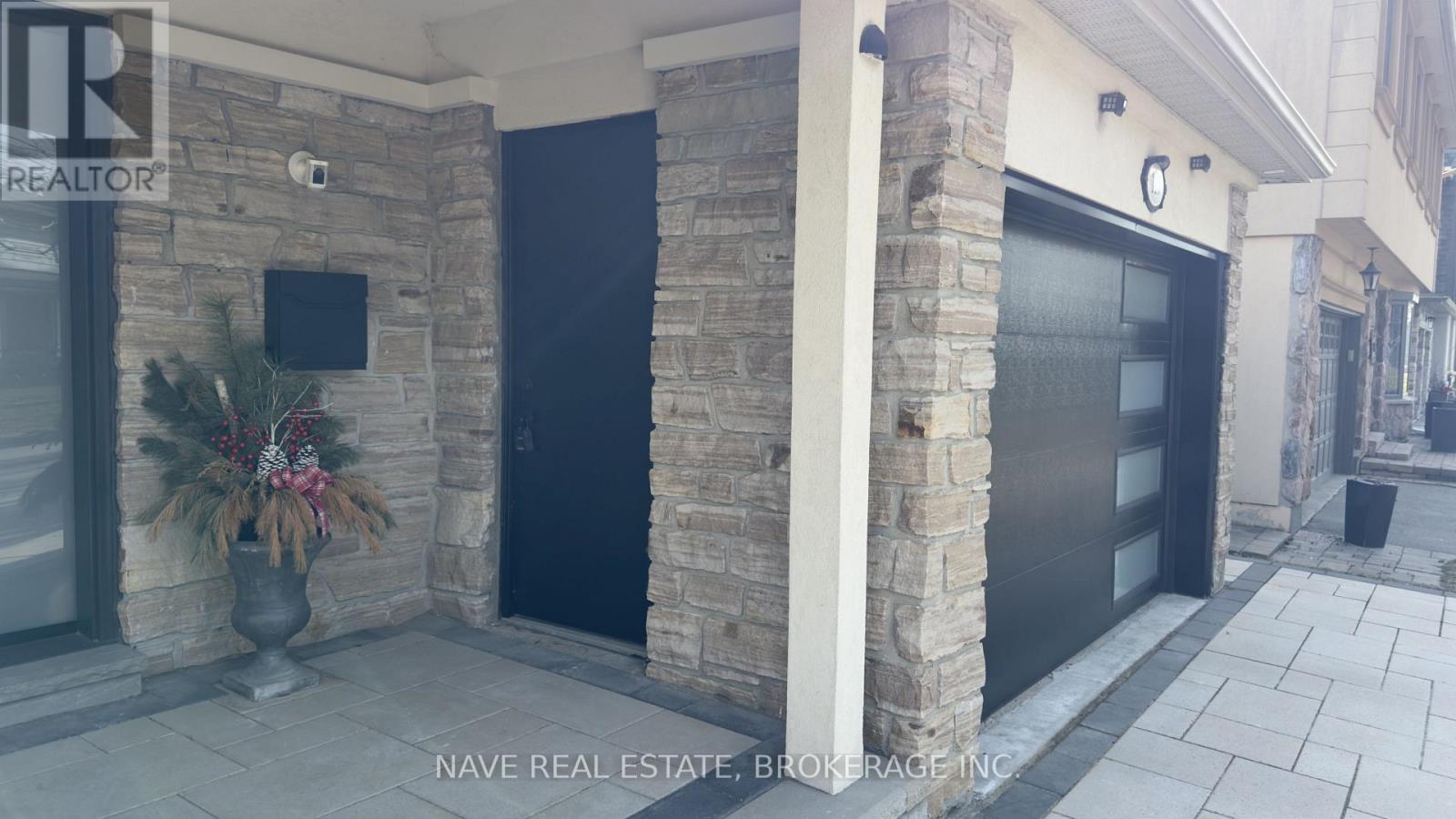 A stone building with a black door and a flat screen TV mounted on the wall.