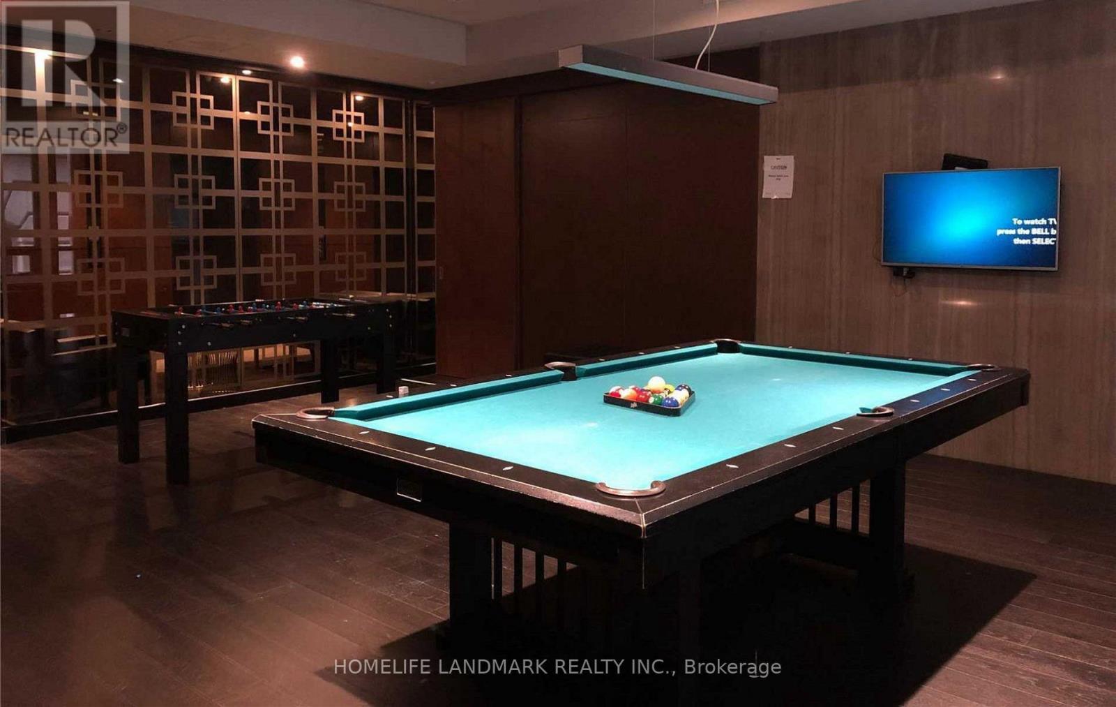 A pool table in a room with a tv on the wall.
