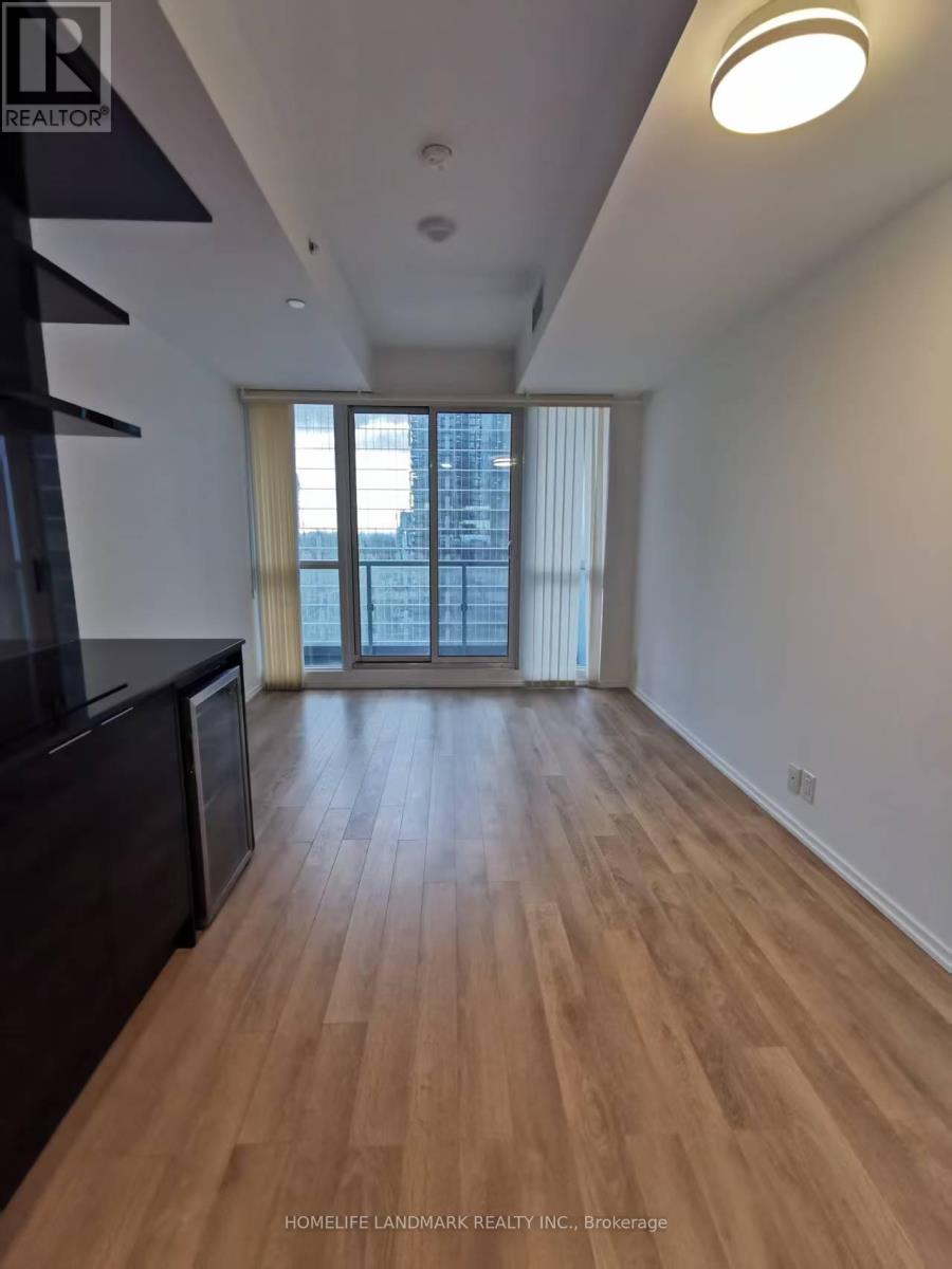 A spacious room with wooden flooring and a large window.