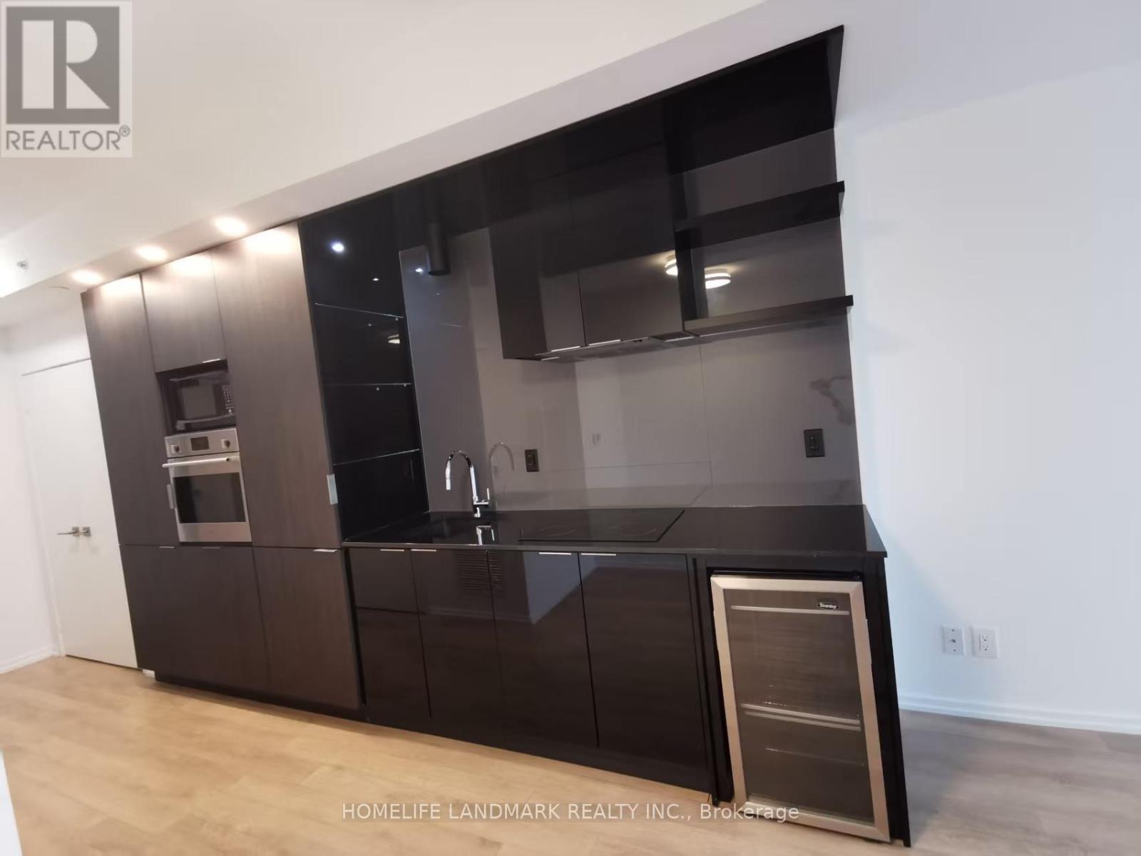 A modern kitchen with dark brown cabinets and a wooden floor.