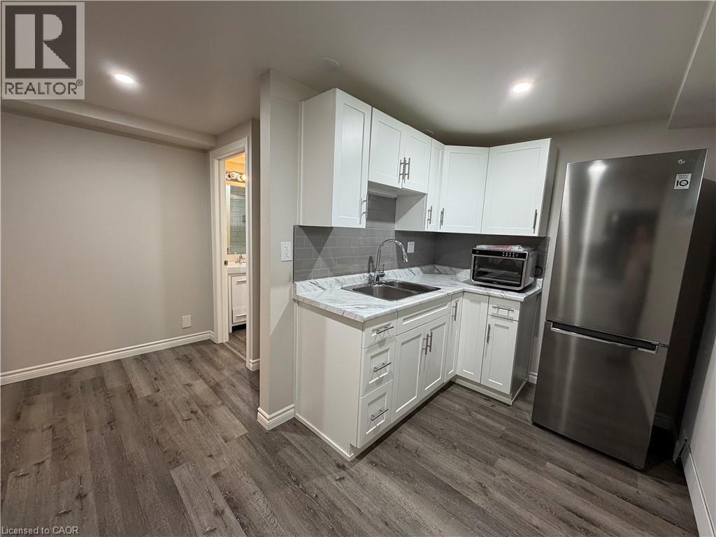 A kitchen with white cabinets and a stainless steel refrigerator.