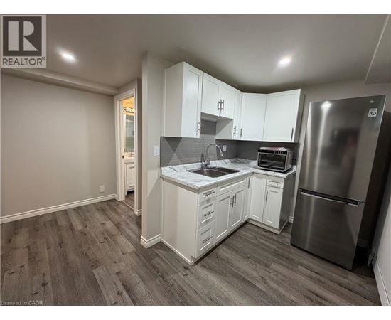 A kitchen with white cabinets and a stainless steel refrigerator.