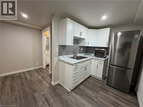 A kitchen with white cabinets and a stainless steel refrigerator.