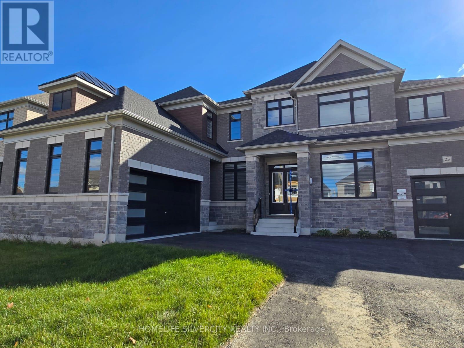 A large, modern house with a stone facade and a driveway leading to the garage.