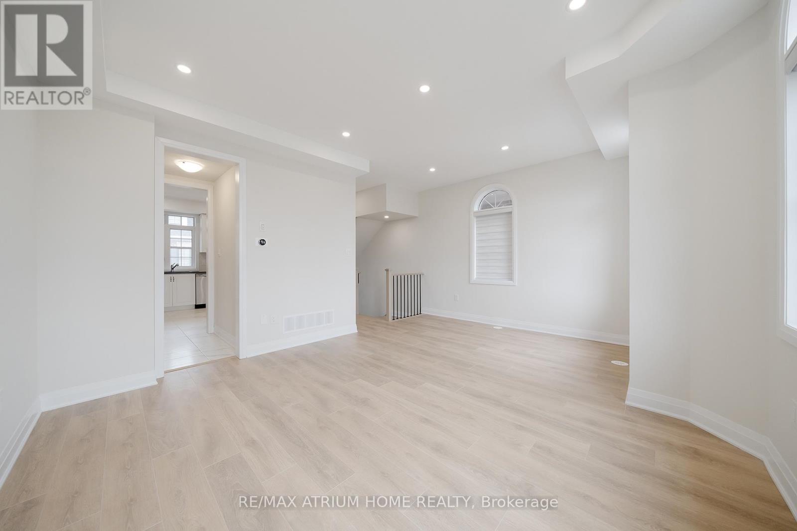 A spacious room with wooden flooring and white walls.