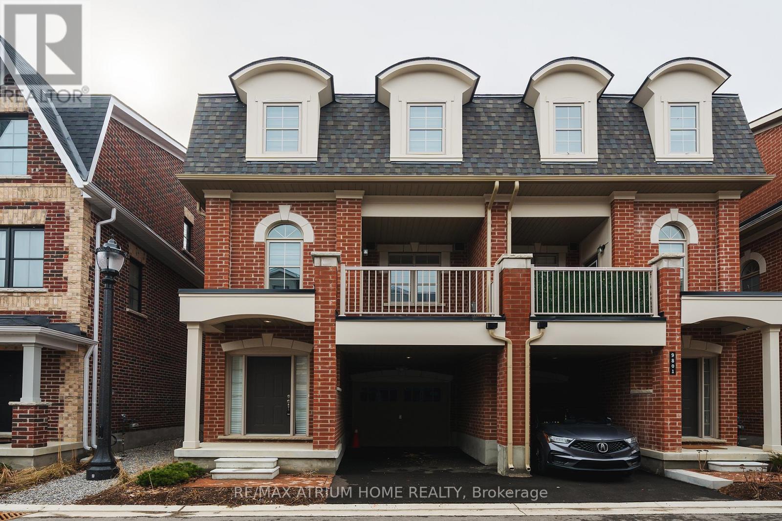 A brick house with a balcony and a car parked in the garage.