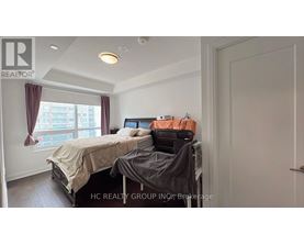 A bedroom with a bed, a desk with a printer, and a window with curtains.