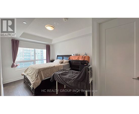 A bedroom with a bed, a desk with a printer, and a window with curtains.