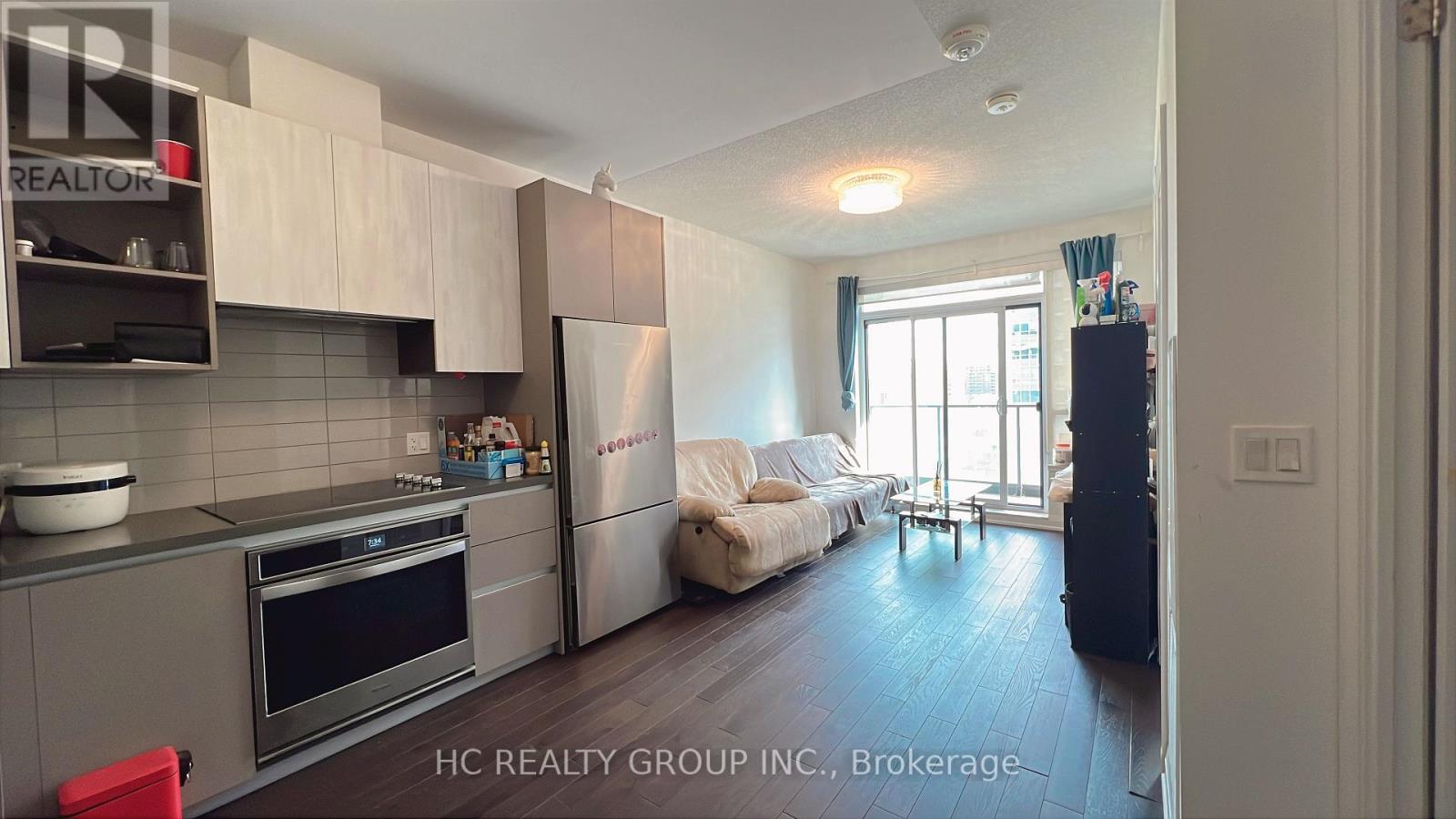 A kitchen with a refrigerator, oven, and sink.