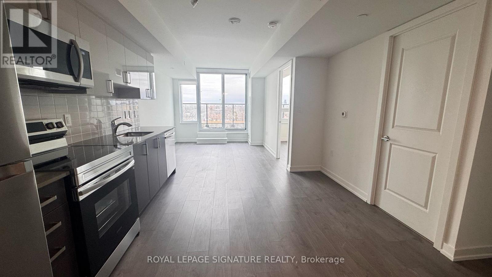 A spacious kitchen with dark wood floors and white walls.
