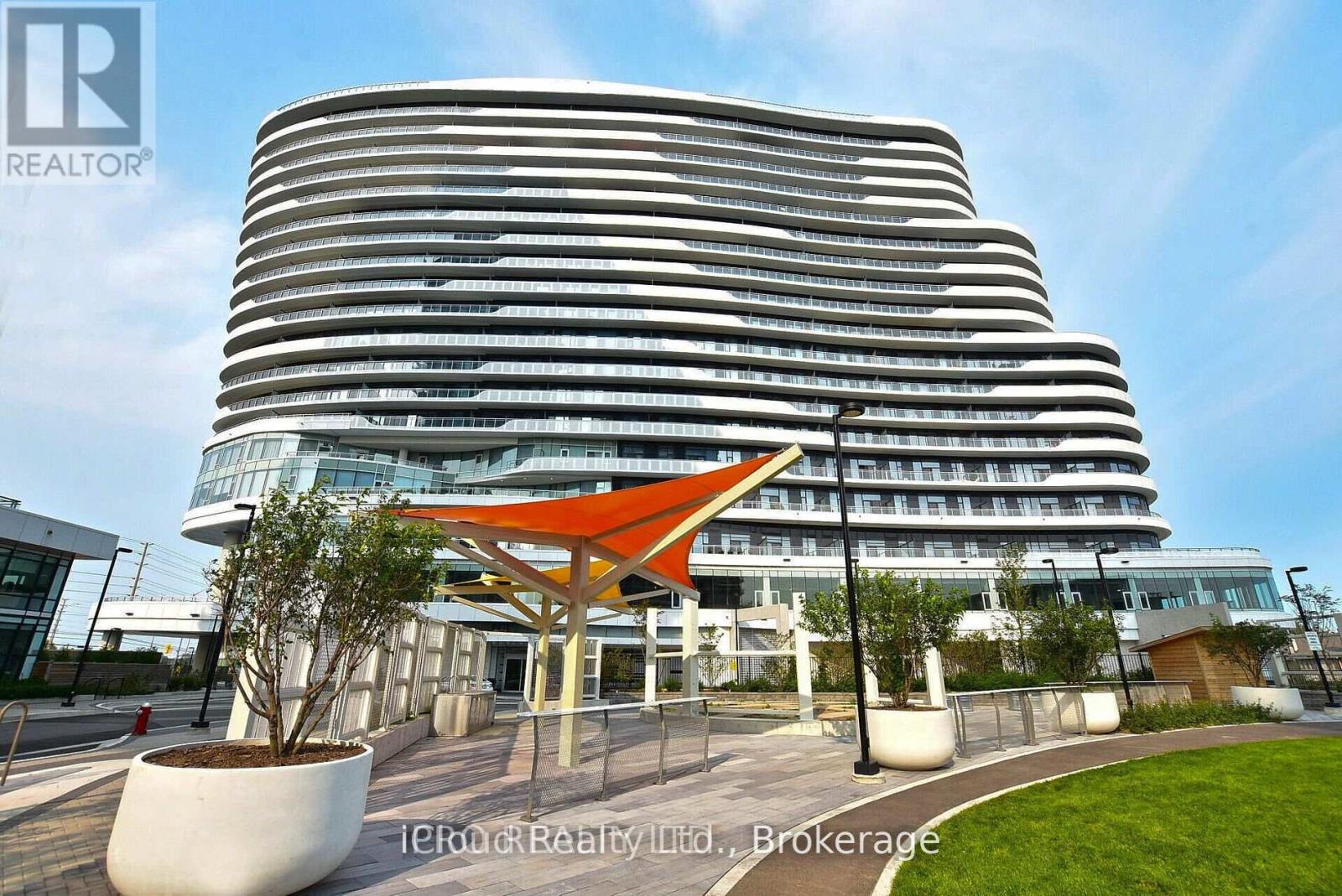 A modern building with a curved facade and a bright orange canopy in front.