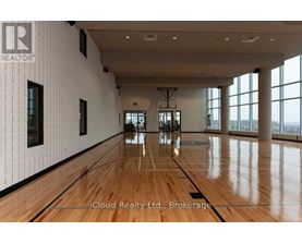 A spacious room with wooden floors and large windows.