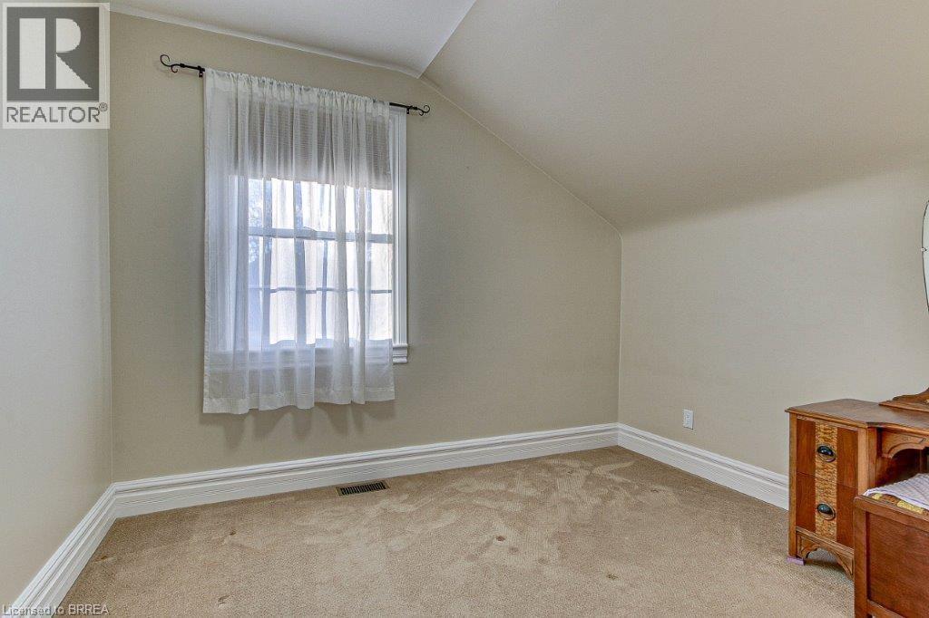 A bedroom with a window covered by a white curtain.