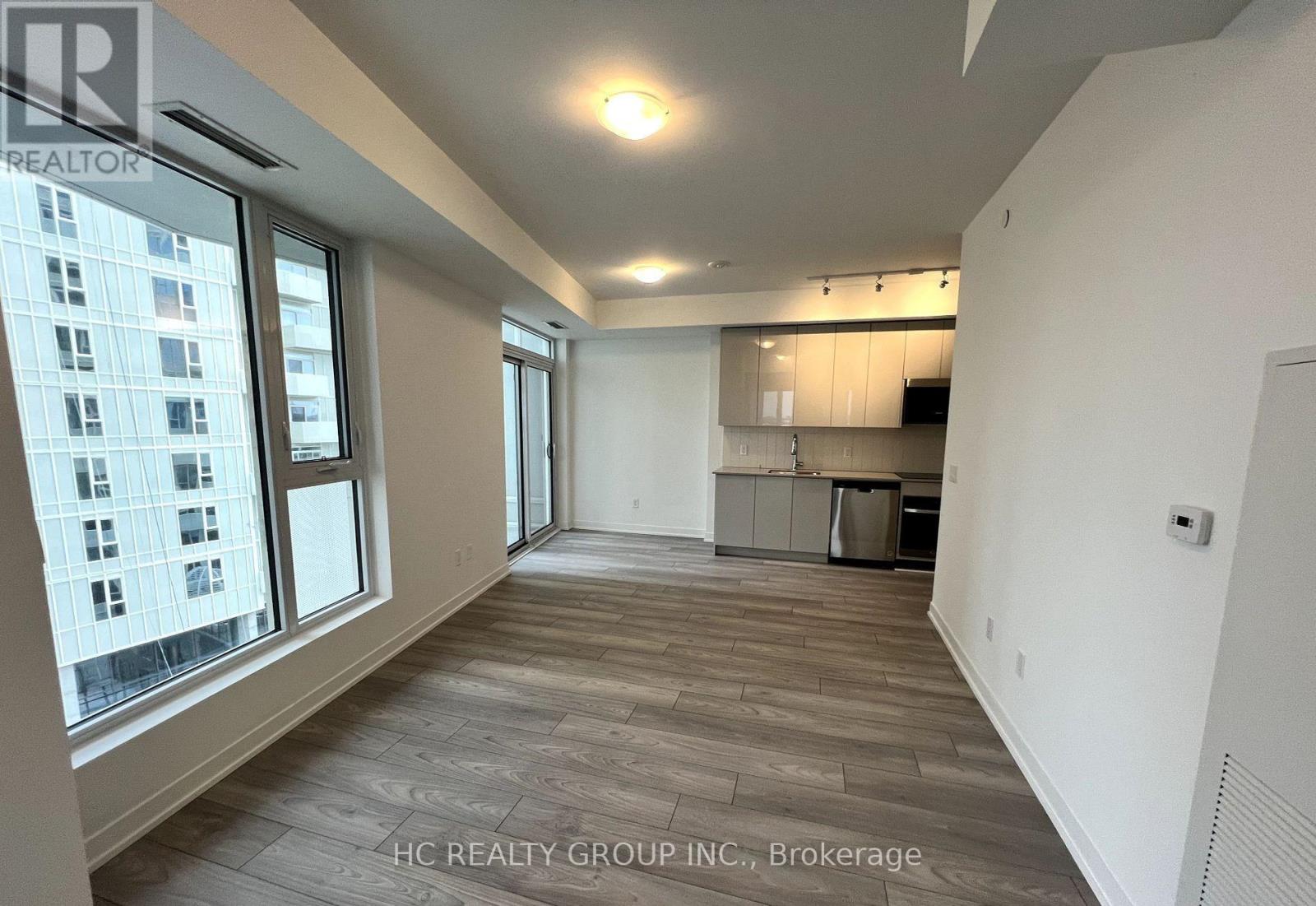 A spacious room with a kitchen area in the background.