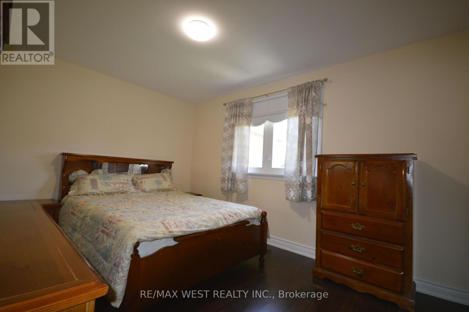 A bedroom with a bed, dresser, and window.