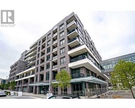 A modern multi-story building with a glass facade and balconies.