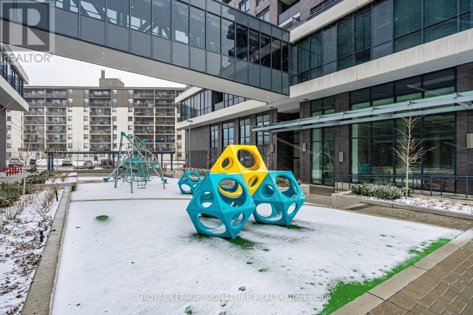 A playground with a blue and yellow structure in the middle of a snowy courtyard.