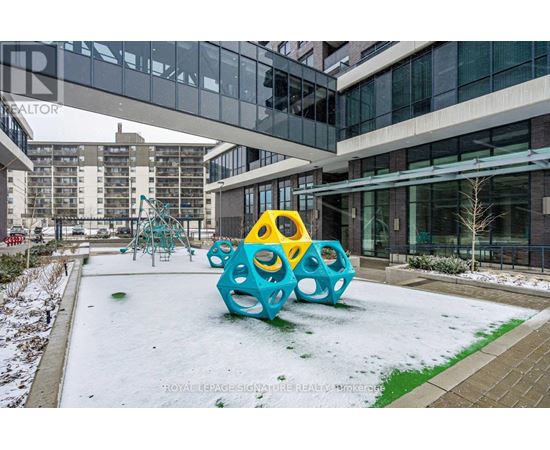 A playground with a blue and yellow structure in the middle of a snowy courtyard.