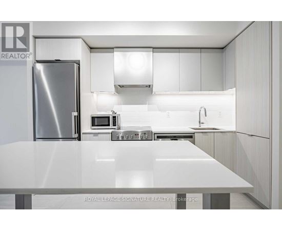 A modern kitchen with white cabinets and stainless steel appliances.