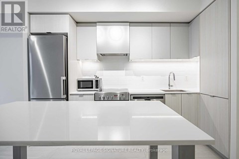A modern kitchen with white cabinets and stainless steel appliances.