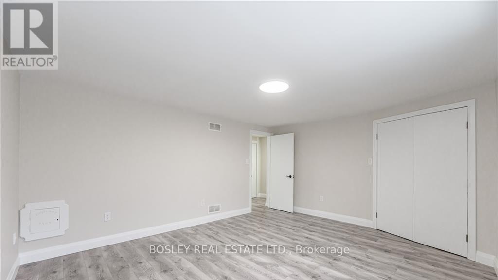 A spacious room with a white ceiling and a wooden floor.