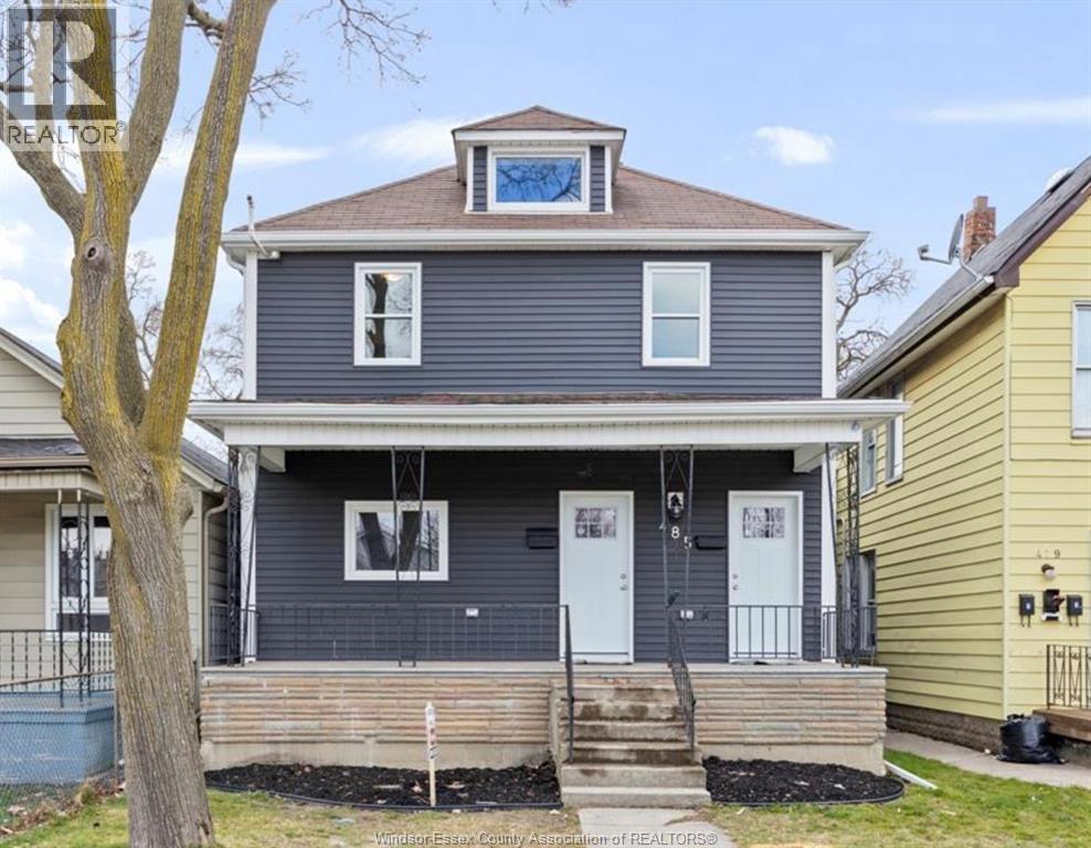 A blue house with a porch and a tree in front.