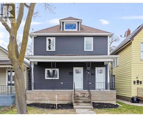 A blue house with a porch and a tree in front.