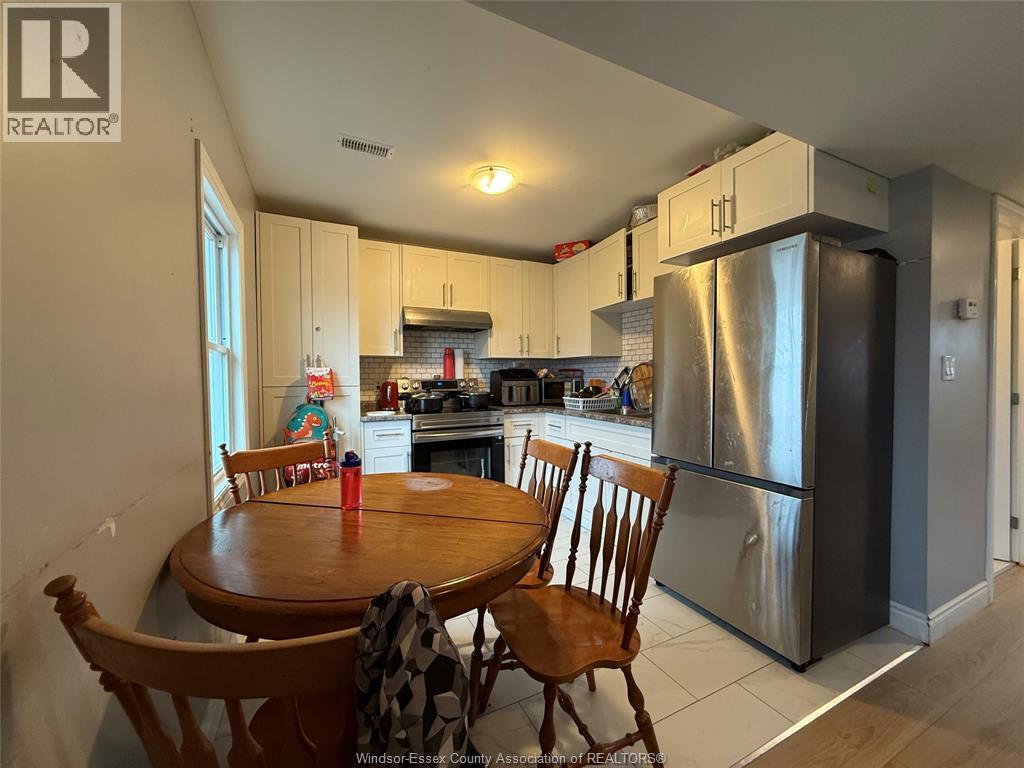 A kitchen with a table and chairs in front of a refrigerator.