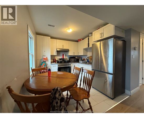 A kitchen with a table and chairs in front of a refrigerator.